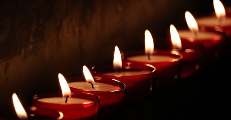 A close-up view of lit candles in a dark, serene setting, creating a warm glow.